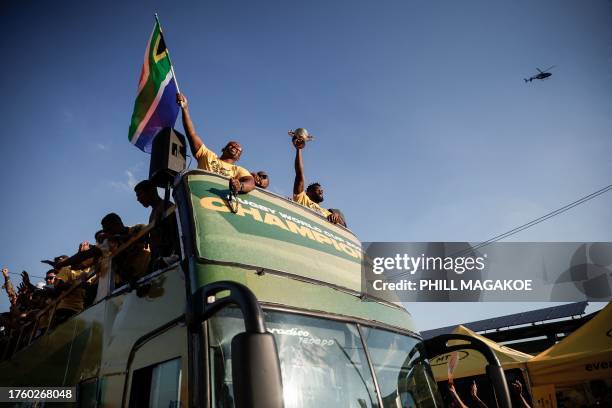 South Africa's flanker and captain Siya Kolisi lifts the Web Ellis Cup as he rides with teammates on a bus during the Springboks Champions trophy...