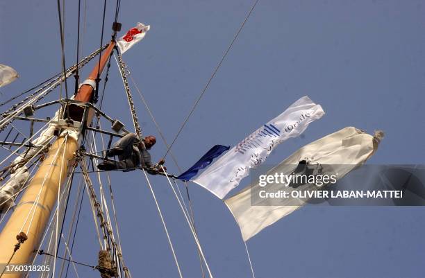 Le lieutenant bosco de la goëlette "La Boudeuse" Ali Berredouane accroche des drapeaux dont le drapeau corse , le 24 juillet 2004 au large de la...
