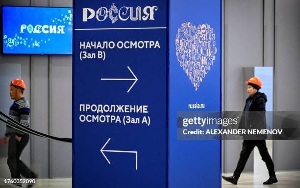 Workers walk past the logotypes of Russia Expo exhibition, designed to demonstrate Russia's main achievements in culture and technology at the...