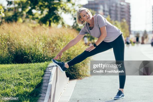 warm up exercise: senior woman stretching before her outdoors training - legging stock pictures, royalty-free photos & images