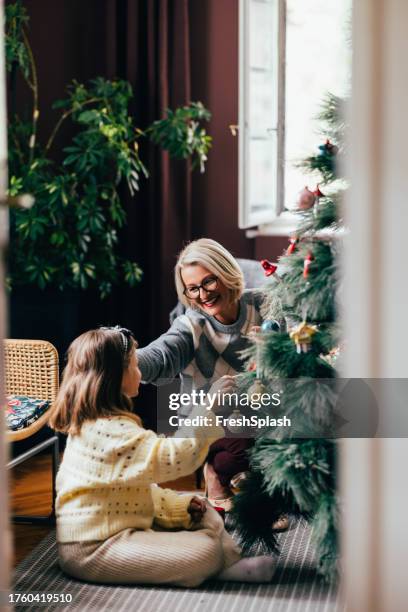 generations of joy: grandmother and granddaughter decorating the christmas tree - decorating the christmas tree stock pictures, royalty-free photos & images
