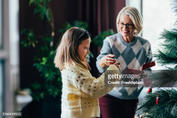 generations of joy: grandmother and granddaughter decorating the christmas tree - christmas eyeglasses stock pictures, royalty-free photos & images