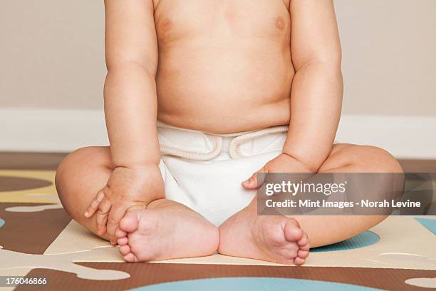 a young 8 month old baby boy wearing cloth diapers, sitting on the floor. - reusable diaper stock pictures, royalty-free photos & images