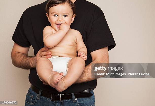 a young boy wearing cloth diapers being held by his father in his arms. - reusable diaper stock pictures, royalty-free photos & images
