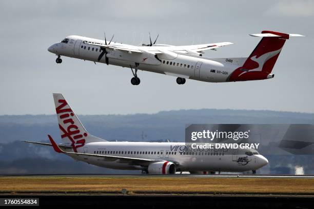 Virgin Airways plane travels down the runway as a QantasLink Dash 8-400 series plane takes off at Sydney's Kingsford Smith international airport on...