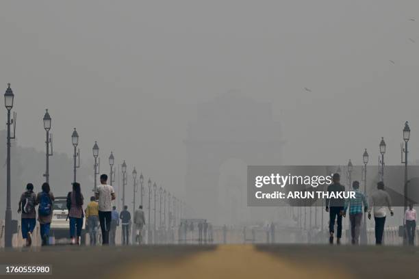 People walk along the Kartavya Path near India Gate amid heavy smog conditions in New Delhi on November 3, 2023. Schools were shut across India's...