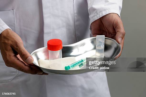 man holding kidney dish with syringe ampule and specimen jar - surgical tray stock pictures, royalty-free photos & images