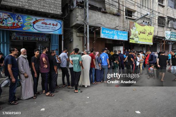 Palestinians wait in front of a bakery shop to meet their daily food needs during the 28th day of Israeli airstrikes in Rafah, Gaza on November 03,...