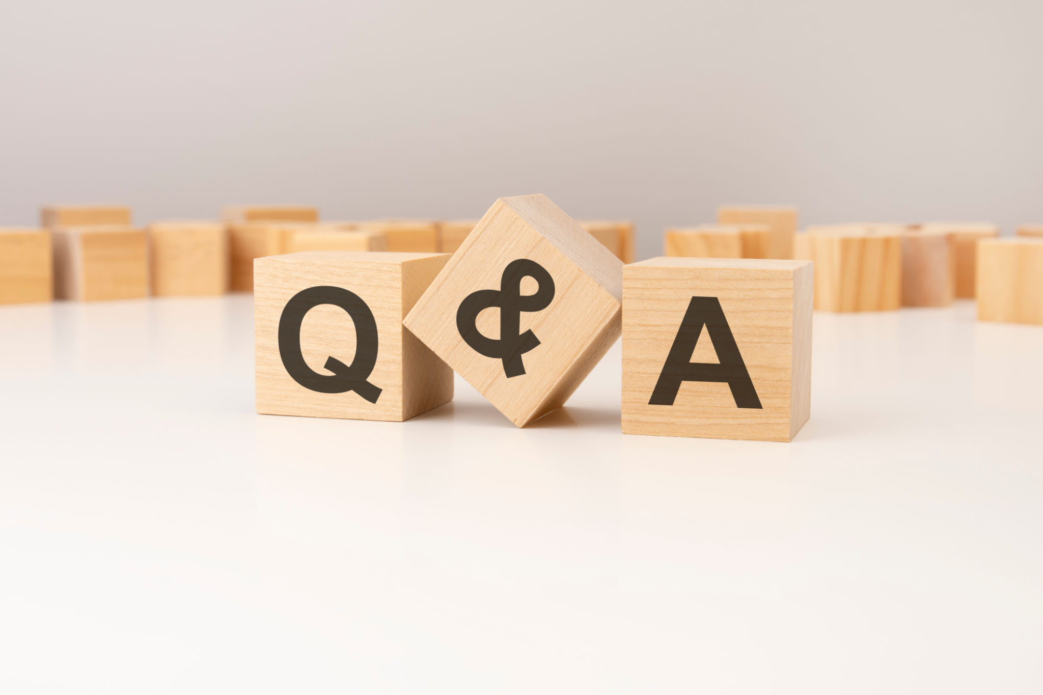 three wooden cubes with Q and A symbols on them. white background. in the background there are many wooden blocks of different sizes three wooden cubes with Q and A symbols on them. white background. in the background there are many wooden blocks of different sizes