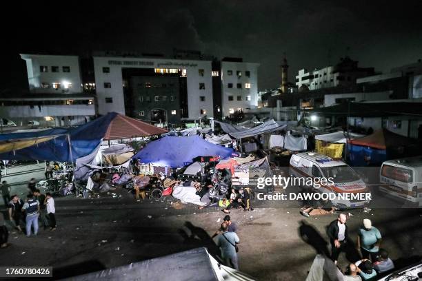People wait in tent shelters in the darkness as fuel for electricity generation runs out, outside Al-Shifa hopsital in Gaza City early on November 3...