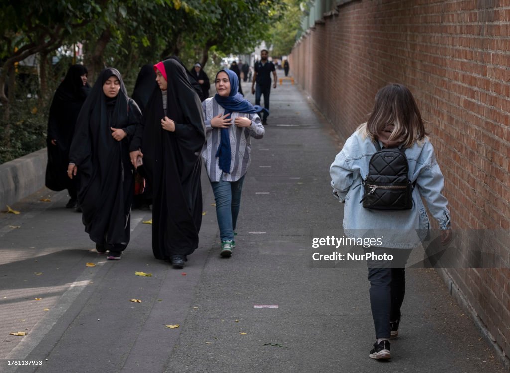 A young Iranian woman without wearing a mandatory headscarf walks