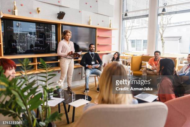 a female black ceo hosting a relaxed weekly business meeting in a cosy co-working space - co presented stockfoto's en -beelden