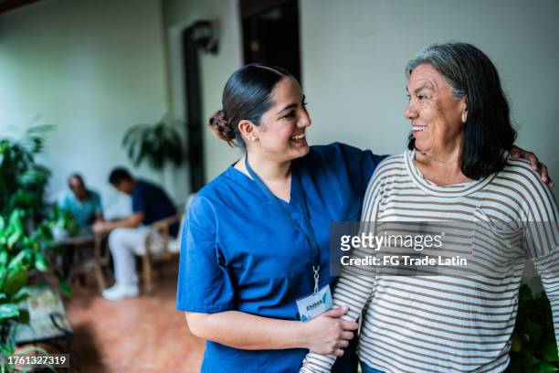 assistente domiciliare che parla con una donna anziana in una casa di cura - servizio a domicilio foto e immagini stock