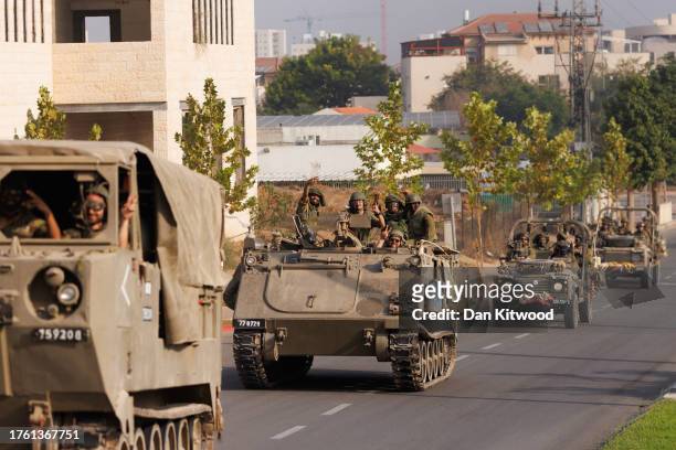 Israeli soldiers give peace and thumbs-up gestures as Israeli tanks and troops move near the border with Gaza on October 28, 2023 in Sderot, Israel....