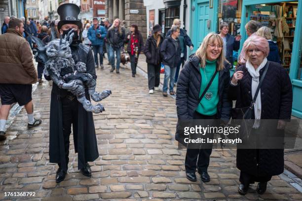 Two women react as they walk past a man in steam punk clothing during Whitby Goth Weekend on October 28, 2023 in Whitby, England. The Whitby Goth...