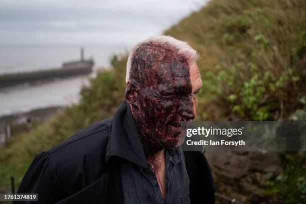 Man made up with make up depicting facial burns attends Whitby Goth Weekend on October 28, 2023 in Whitby, England. The Whitby Goth Weekend is an...