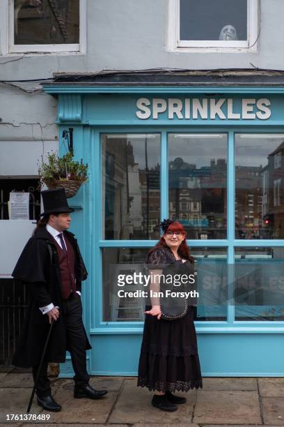 Couple in Gothic style clothing walk past a shop as they attend Whitby Goth Weekend on October 28, 2023 in Whitby, England. The Whitby Goth Weekend...