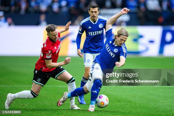 Lino Tempelmann of Schalke is challenged by Cedric Teuchert of Hannover during the Second Bundesliga match between FC Schalke 04 and Hannover 96 at...