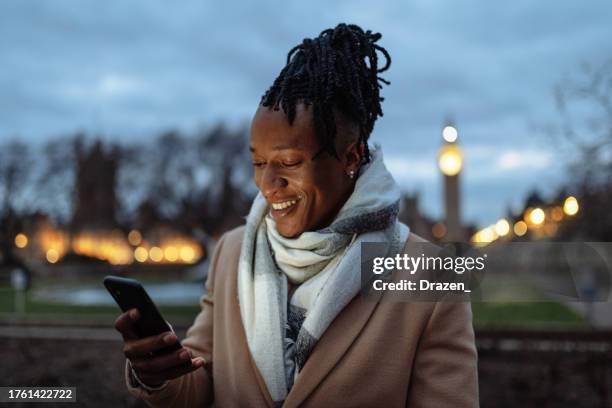 british youth in wintertime, outdoors, standing near big ben and using smart phone - northern european descent stock pictures, royalty-free photos & images