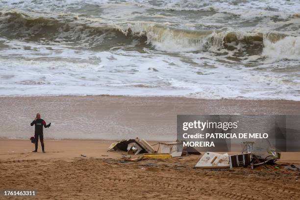 Man in a diving suit stands next to wreckage of a sailing boat on Azul beach at Santa Cruz, after the vessel capsized off the coast of the...