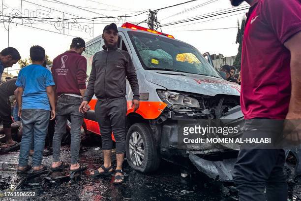 People gather around an ambulance damaged in a reported Israeli strike in front of Al-Shifa hospital in Gaza City on November 3 as battles between...