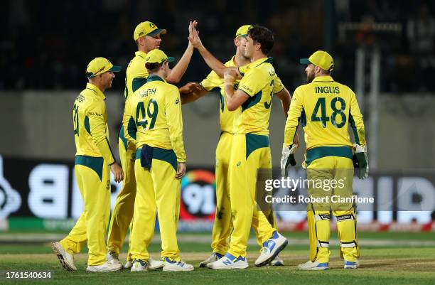 Pat Cummins of Australia celebrates with teammates after taking the wicket of Matt Henry of New Zealand during the ICC Men's Cricket World Cup India...