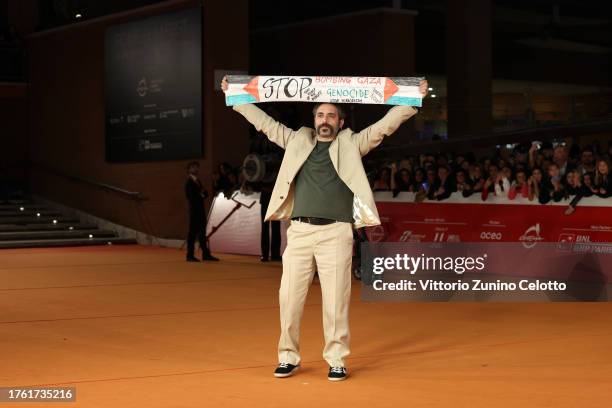 Antonio De Matteo, holding a banner to demonstrate solidarity with the Palestinian people and demand ceasefire, attends a red carpet for the movie...