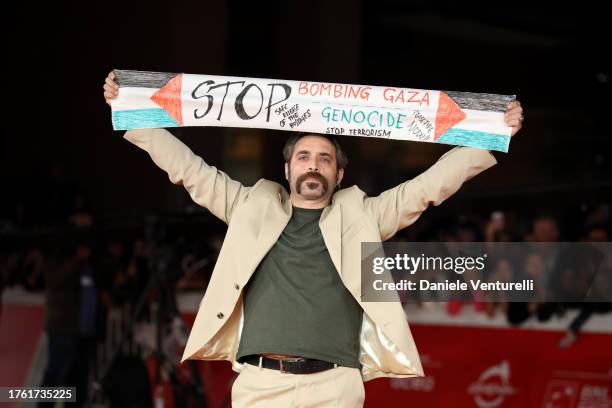 Antonio De Matteo, holding a banner to demonstrate solidarity with the Palestinian people and demand ceasefire, attends a red carpet for the movie...