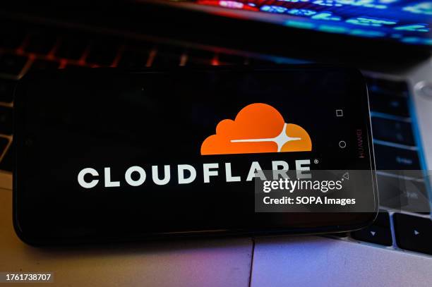 In this photo illustration a CloudFlare logo is displayed on a smartphone with stock market percentages on the background.