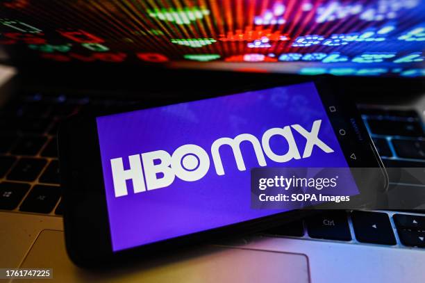In this photo illustration, a HBOmax logo is displayed on a smartphone with stock market percentages on the background.
