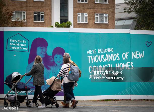 Hoardings advertising a development of new council homes is erected beside dwellings that were originally built as social housing for the local...