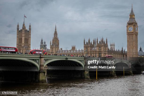 Buses and people pass over Westminster Bridge as grey clouds gather behind the recently restored Big Ben or Elizabeth Tower, the clock tower of the...