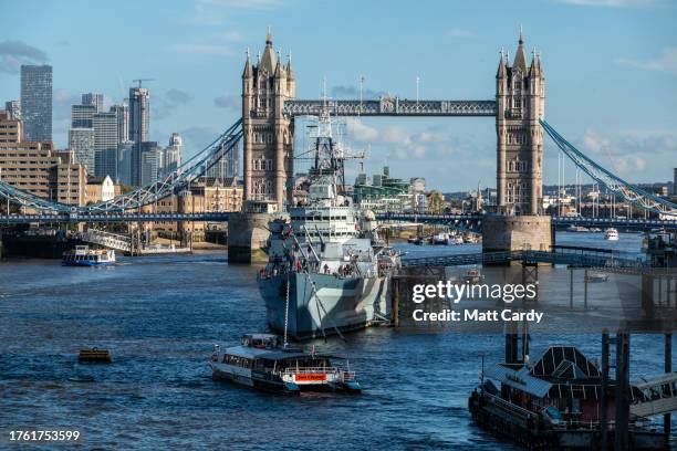 The sun shines on HMS Belfast, a historic tourist attraction which is moored on the River Thames near Tower Bridge on October 24, 2023 in London,...