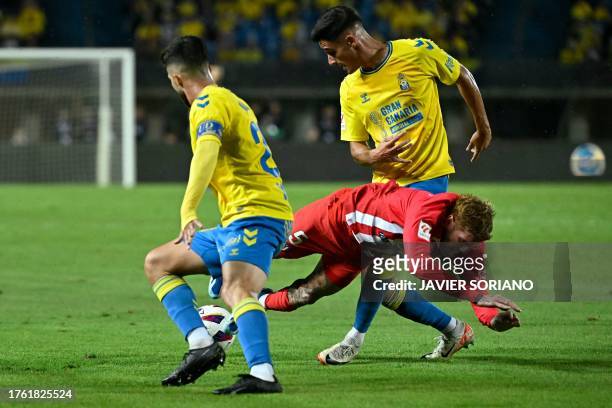 Atletico Madrid's Argentinian midfielder Rodrigo De Paul falls down as he is challenged by Las Palmas' Spanish midfielder Kirian Rodríguez and Las...