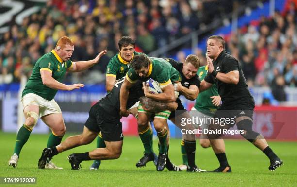 Eben Etzebeth of South Africa is tackled by Codie Taylor and Sam Cane of New Zealand during the Rugby World Cup Final match between New Zealand and...