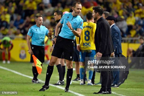 Spanish referee Mario Melero Lopez talks with Atletico Madrid's Argentinian coach Diego Simeone during the Spanish league football match between UD...