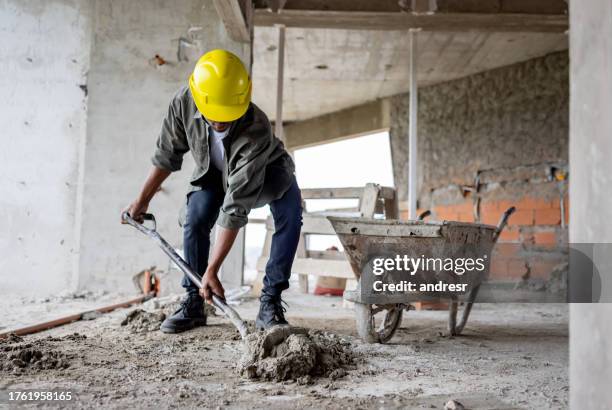 construction worker picking up cement on a wheelbarrow - cement stock pictures, royalty-free photos & images