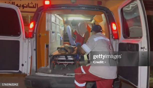 Graphic content / This image grab taken from an AFPTV video footage shows Palestinian medics carrying an injured youth to an ambulance outside the...