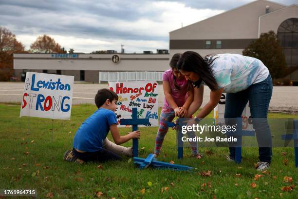 Bre Allard, along with her children Zeke Allard and Lucy Allard place crosses and signs in front of the Sparetime Recreation, recently renamed...