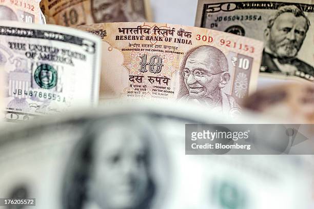 Indian rupee and U.S. Dollar banknotes are arranged for a photograph in Mumbai, India, on Saturday, Aug. 10, 2013. India plans to sell 220 billion...