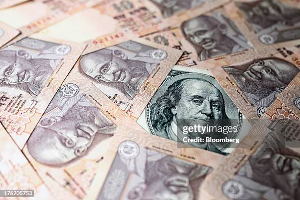 Indian rupee and U.S. Dollar banknotes are arranged for a photograph in Mumbai, India, on Saturday, Aug. 10, 2013. India plans to sell 220 billion...