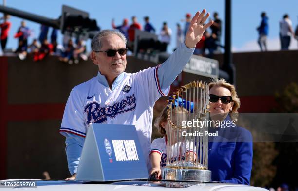 Texas Rangers manager Bruce Bochy and his wife Kim Seib ridie with the World Series trophy and wave to fans lining the street and buildings during...
