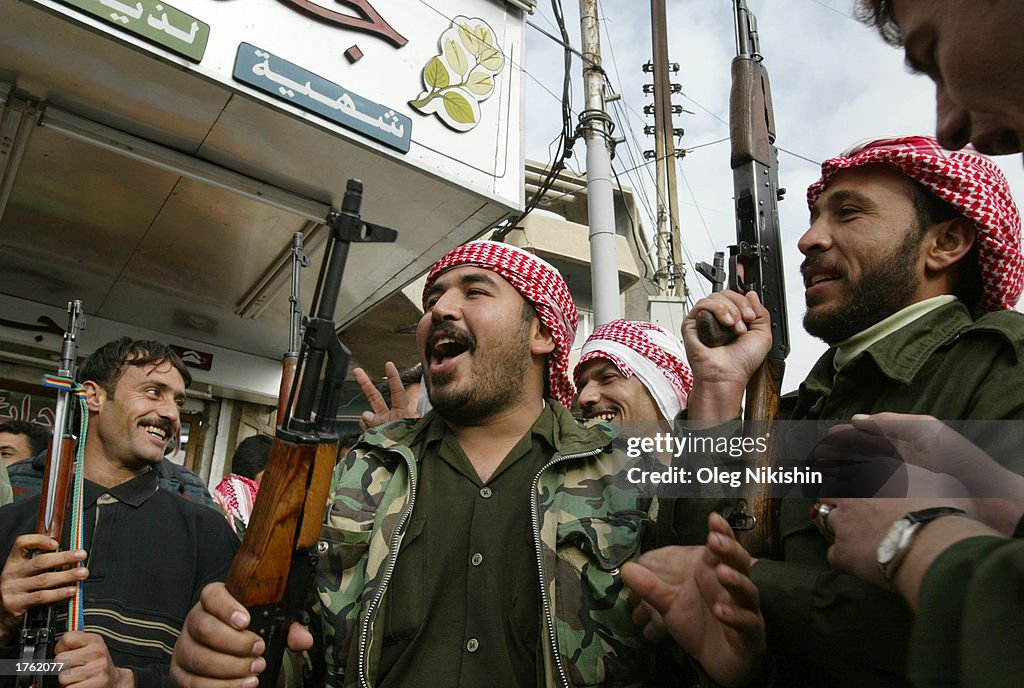 Iraqi men hold an AK-47 rifle before a parade