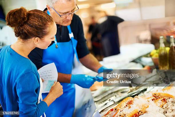 fishmonger helping a customer - fishmonger stock pictures, royalty-free photos & images