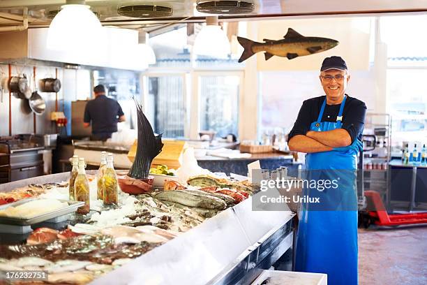 sorridente fishmonger in negozio - pescivendolo foto e immagini stock