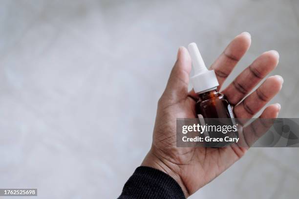 woman holds bottle of prescription nasal spray - nasenspray stock-fotos und bilder