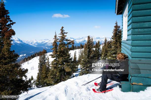 snowshoer resting atop a mountain, lake louise - skigebied stockfoto's en -beelden