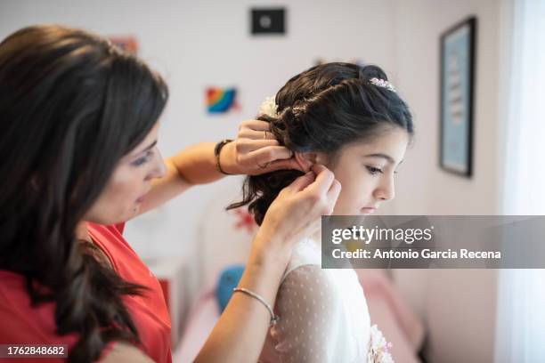 on the day of her communion a mother dresses her daughter - forma-di-comunicazione foto e immagini stock