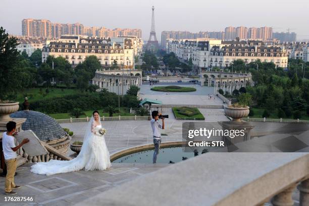 This picture taken on August 7, 2013 shows a woman posing for wedding photos with the background of a replica of the Effel Tower in Tianducheng, a...