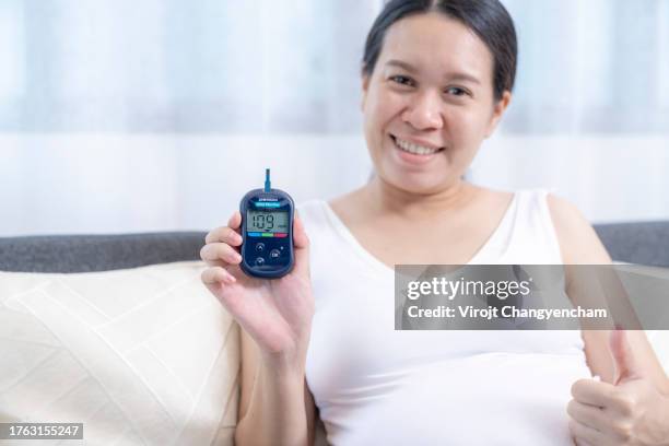 pregnant woman on sofa with blood sugar test result - blood sugar test stock pictures, royalty-free photos & images